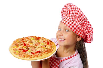 Kid wearing a chef hat holding up a homemade pizza