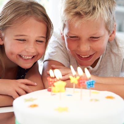boy and girl smiling at candles on a birthday cake