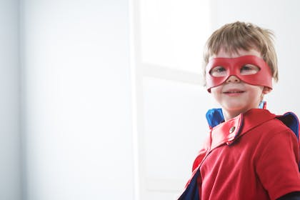 Little boy dressed as a superhero wearing red eye mask