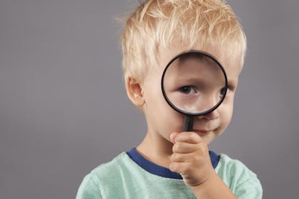 Boy holding magnifying glass up to face