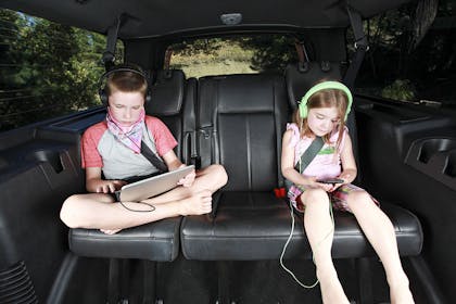 Kids with devices on the backseat of a car